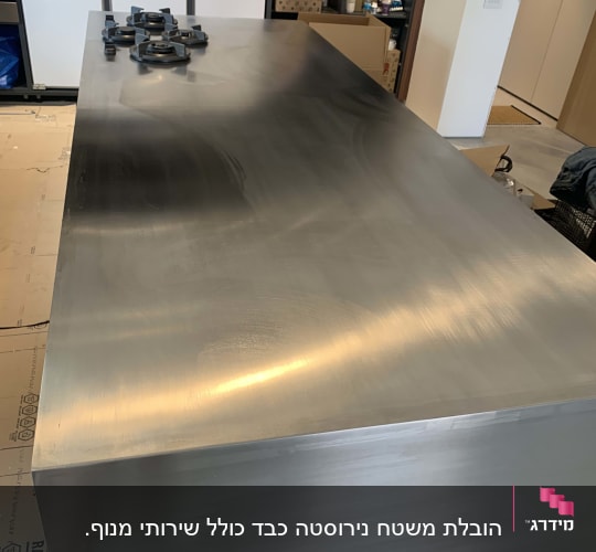 משטח מתכת גדול עם חלקים מונחים עליו בחדר עבודה.